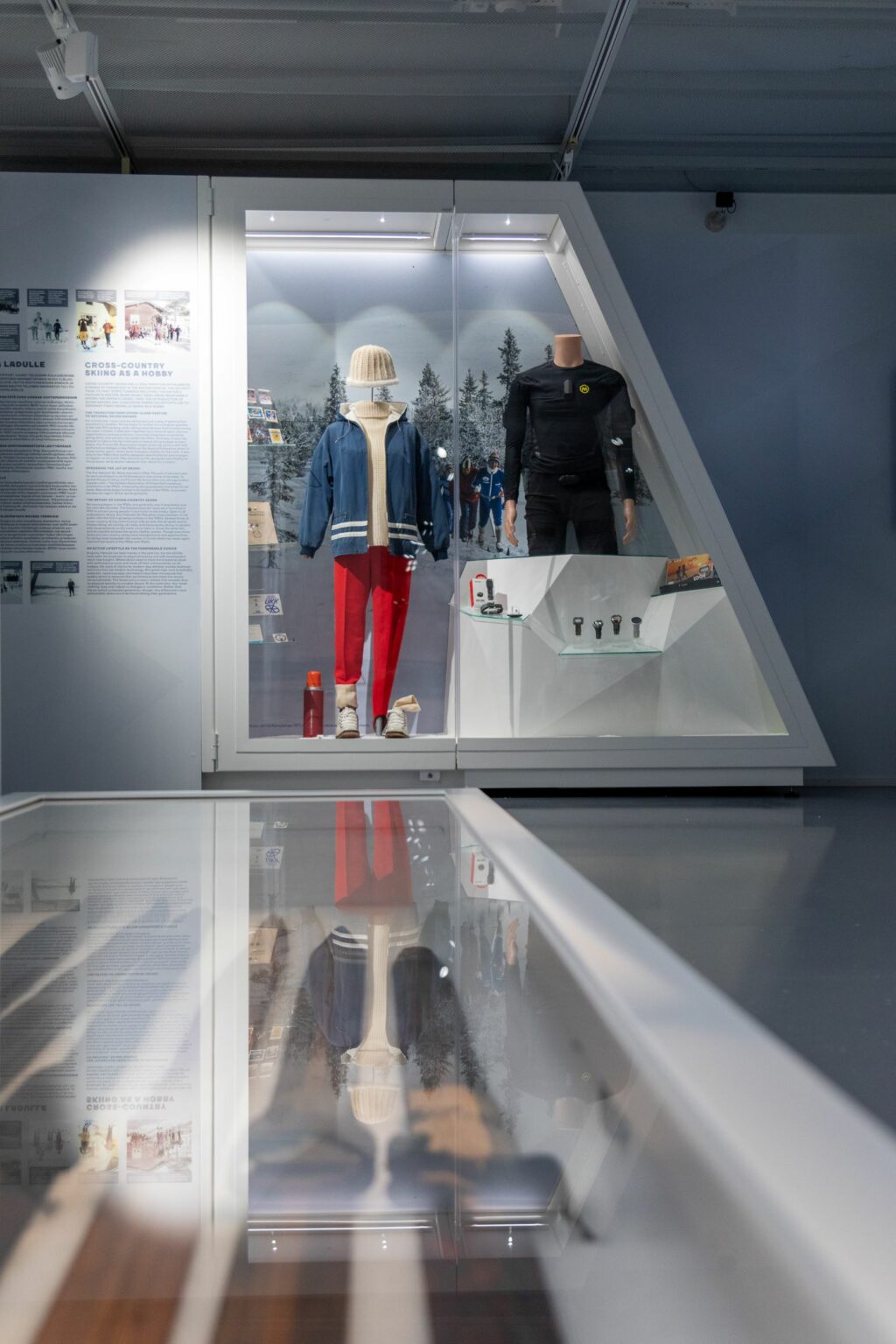 Värikuva Hiihtomuseon näyttelyn vitriinissä, jossa hiihtoaiheista esineistöä.