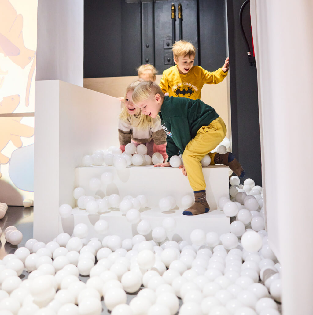 Hymyileviä lapsia Lumi-näyttelyn lumitunneli pallomeressä.